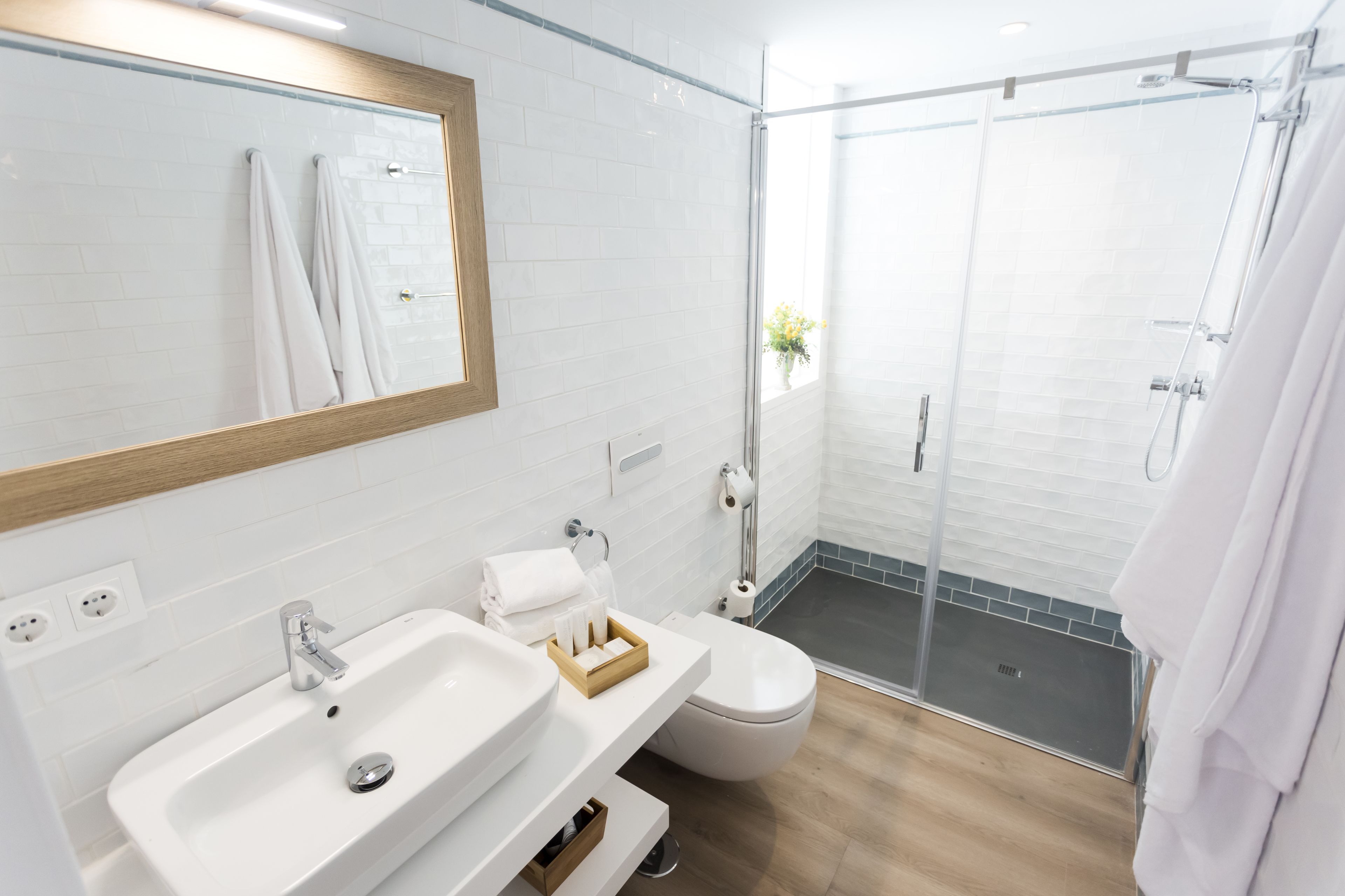 Un baño moderno con lavamanos blanco, inodoro y cabina de ducha con paredes de vidrio.