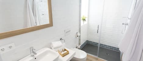 Un baño moderno con lavamanos blanco, inodoro y cabina de ducha con paredes de vidrio.