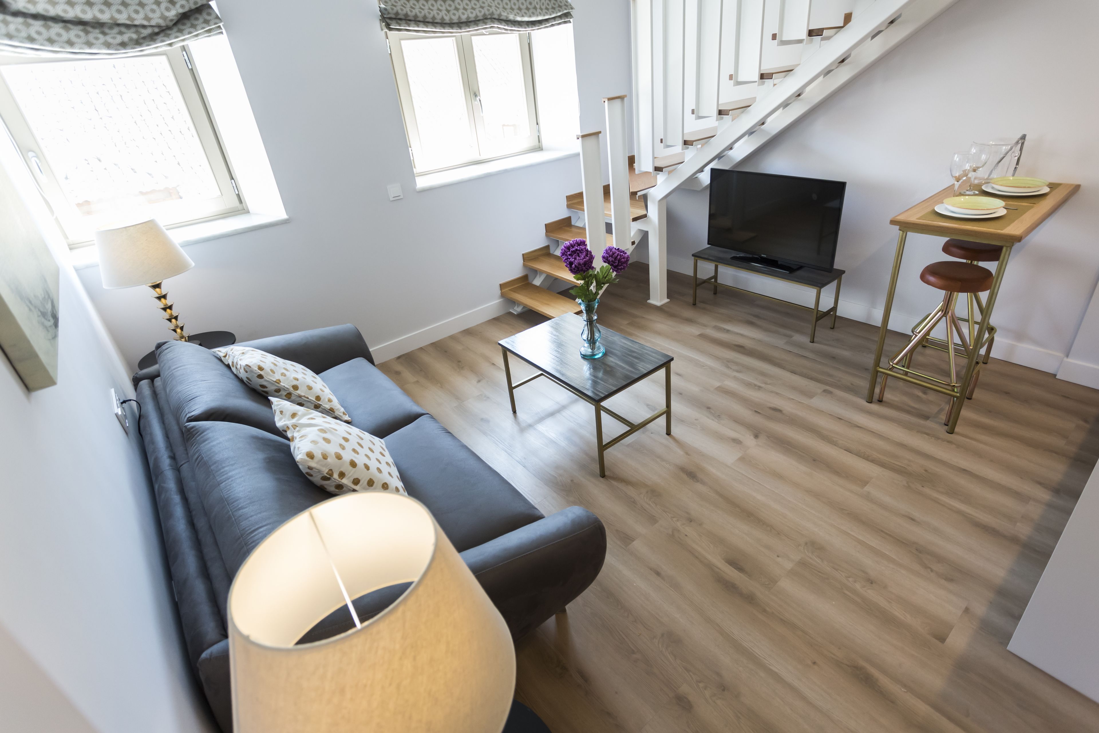 A modern living room with a sofa, a coffee table, a TV, and a dining area with a table and chairs.
