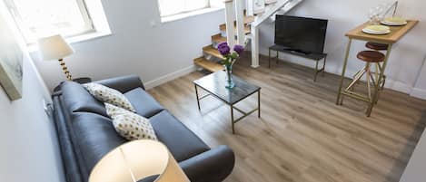 A modern living room with a sofa, a coffee table, a TV, and a dining area with a table and chairs.