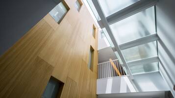 Een modern gebouw met een houten gevel, grote ramen en een glazen balkon.