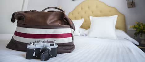 A bed with a striped bag and a vintage camera on it.