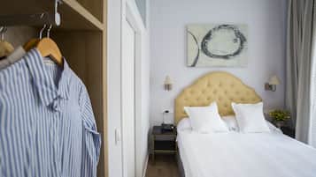 Hotellihuone, jossa on sänky, yöpöytä, lamppu, seinätaideteos ja vaatekaappi.