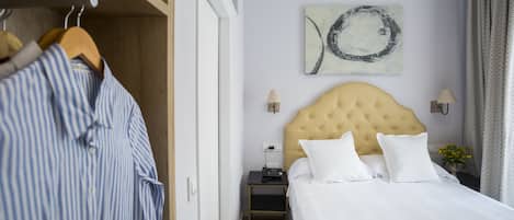 Une chambre d’hôtel comprenant un lit, une table de chevet, une lampe, un tableau ou une œuvre d’art mural et une armoire.