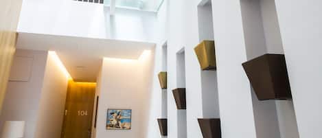 Ein modernes Interieur mit einer Glasstufenwendel, weißen Wänden und geometrischen Wandleuchten.