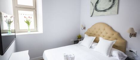 A hotel room with a bed, bedside table, lamp, and artwork on the wall.