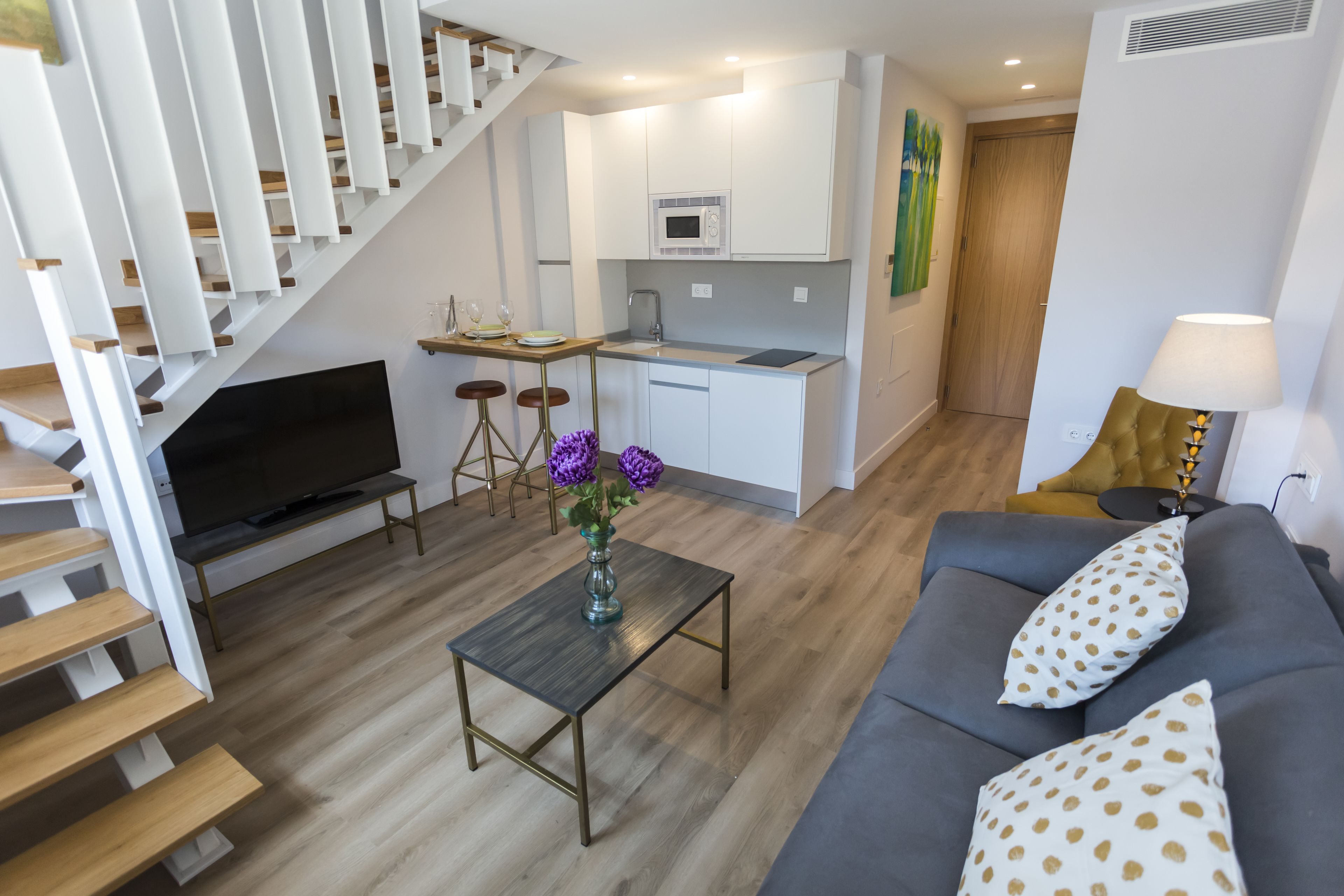 Un apartamento moderno con sala de estar, cocina y escalera.