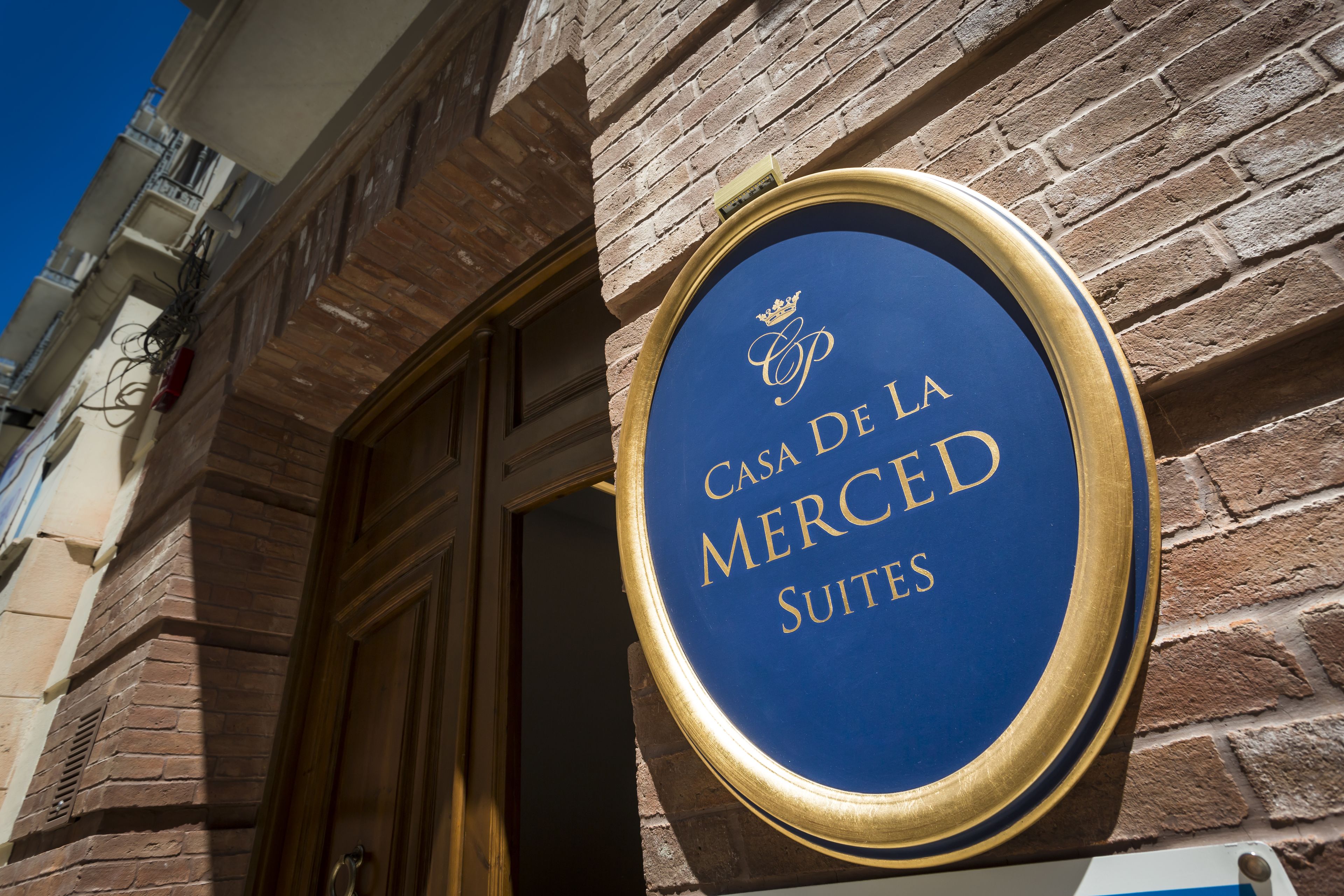 A sign for Casa De La Mercé Suites, indicating a hotel or accommodation.