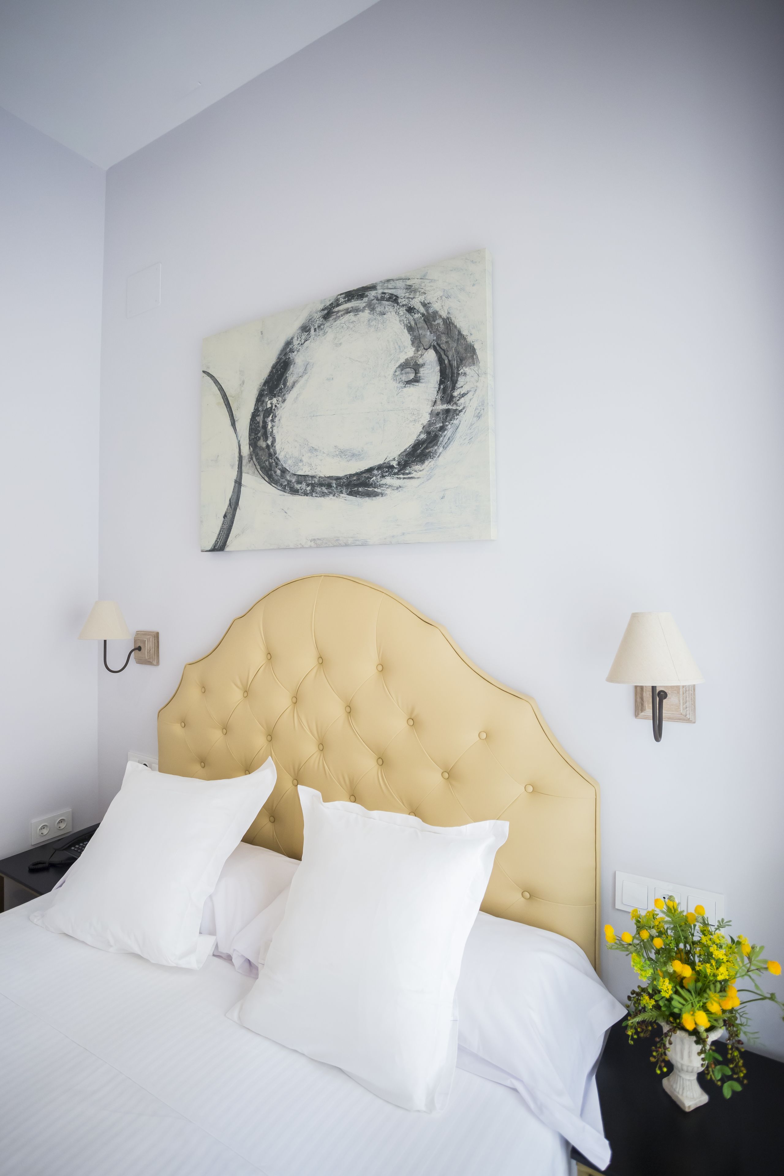 A neatly made bed with a tufted headboard, white bedding, and a single white pillow.