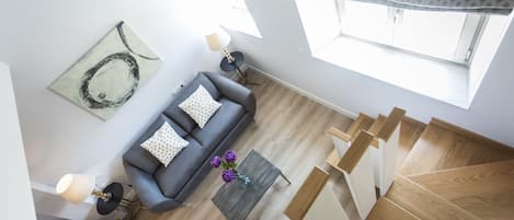 A modern living room with a grey sofa, yellow armchair, and a wooden staircase.