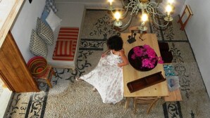 A cozy room with a wooden table, a patterned rug, and a chandelier. - Cosmos Home Lindos (Rhodes)