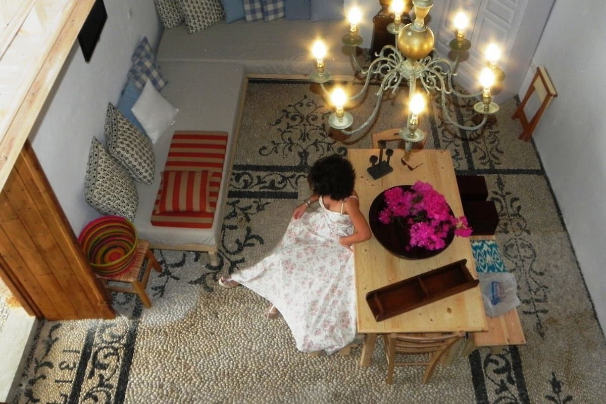 A cozy room with a wooden table, a patterned rug, and a chandelier.