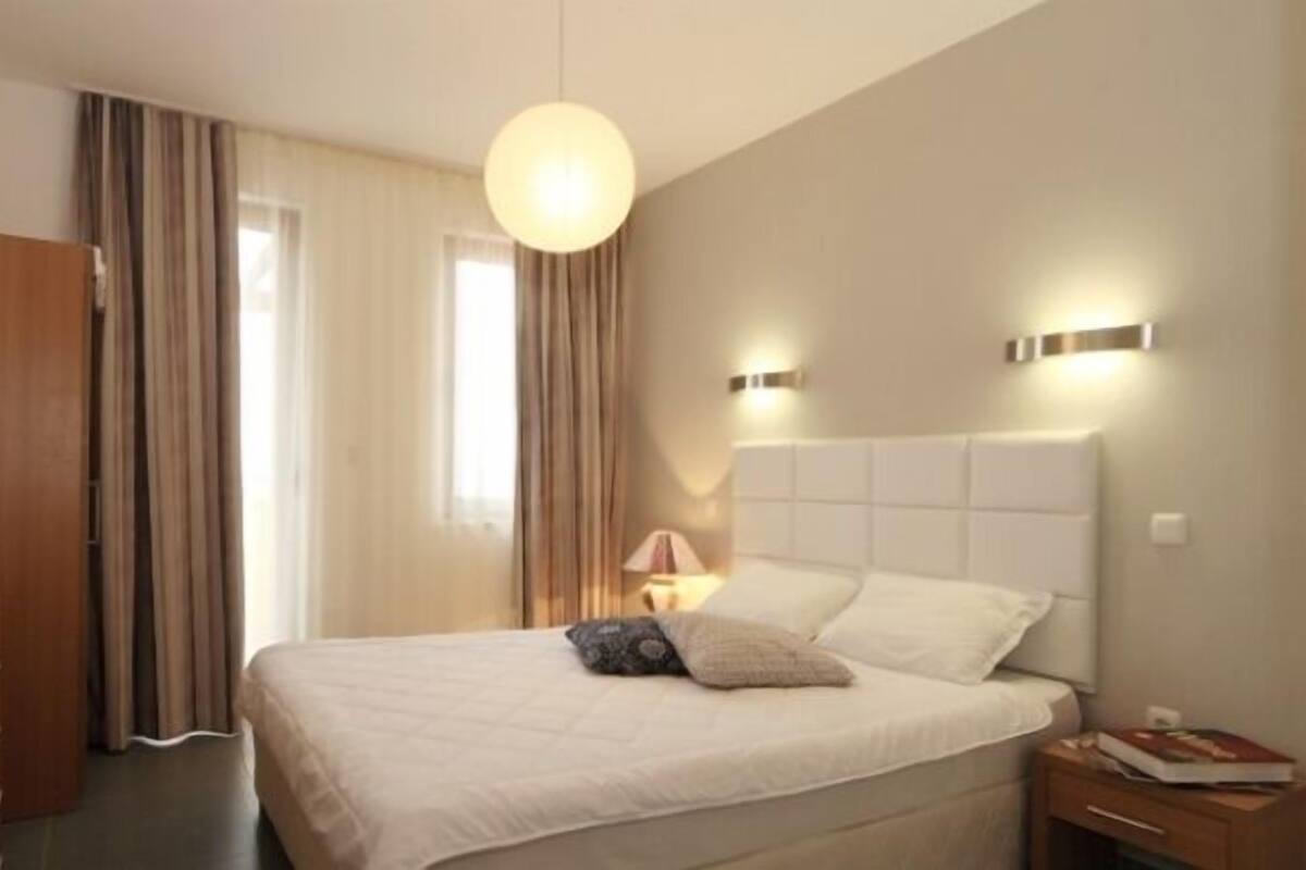 Ein Hotelzimmer mit einem großen Bett, einem Schreibtisch mit Lampe und Vorhängen an den Fenstern.