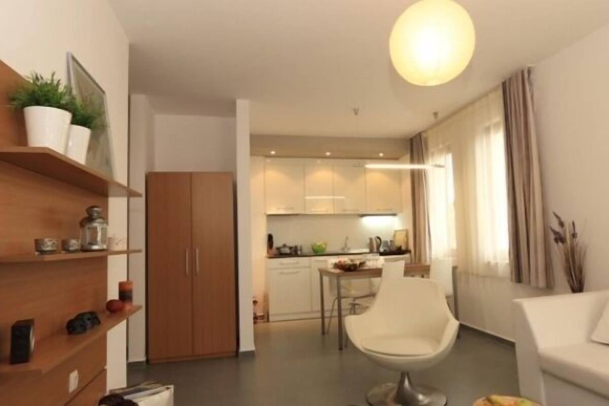 Eine moderne Wohnung mit Wohnbereich, Küchenzeile und Essplatz.