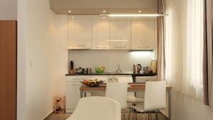 Una cocina moderna con armarios blancos, una mesa de comedor con sillas y un ventanal con cortinas.
