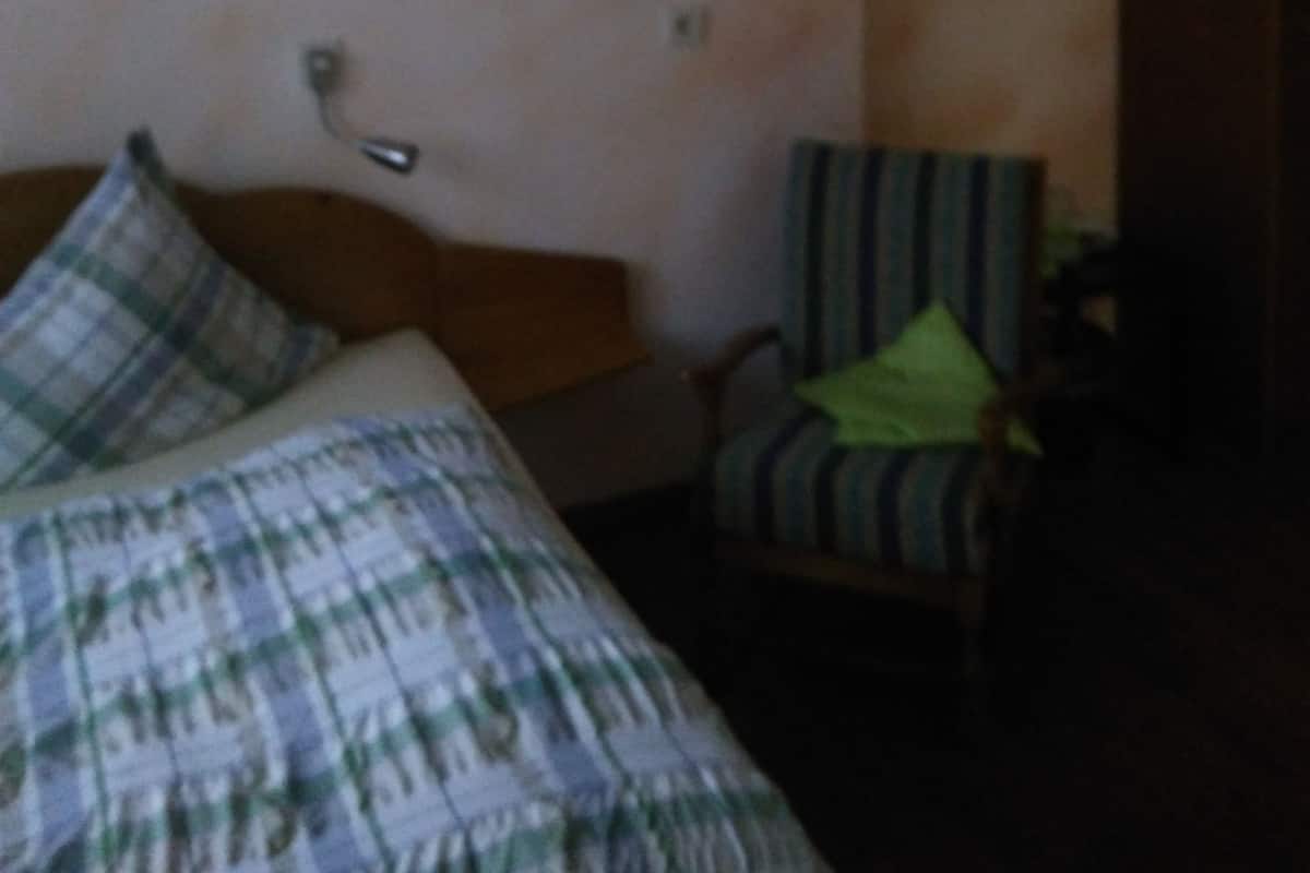 A bedroom with a bed, a chair, and a lamp.