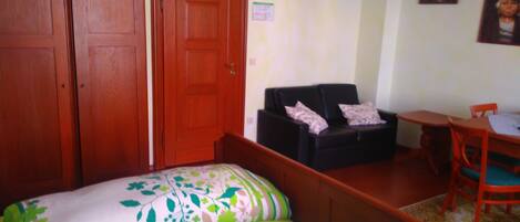 A room with two beds, a desk, a chair, and two wardrobes.