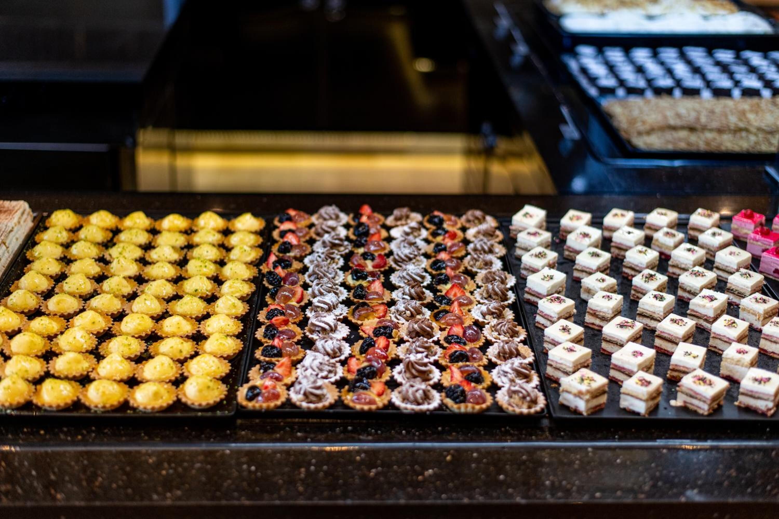 Een presentatie van diverse gebakjes en desserts in een bakkerij.