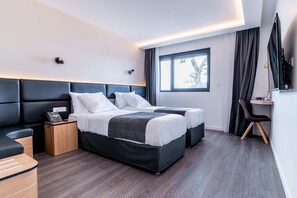 Une chambre d’hôtel moderne avec un grand lit, des tables de chevet, un bureau et une télévision.