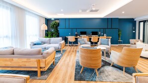 Un salon moderne avec des canapés, des fauteuils, un coin repas et une cuisine en arrière-plan.
