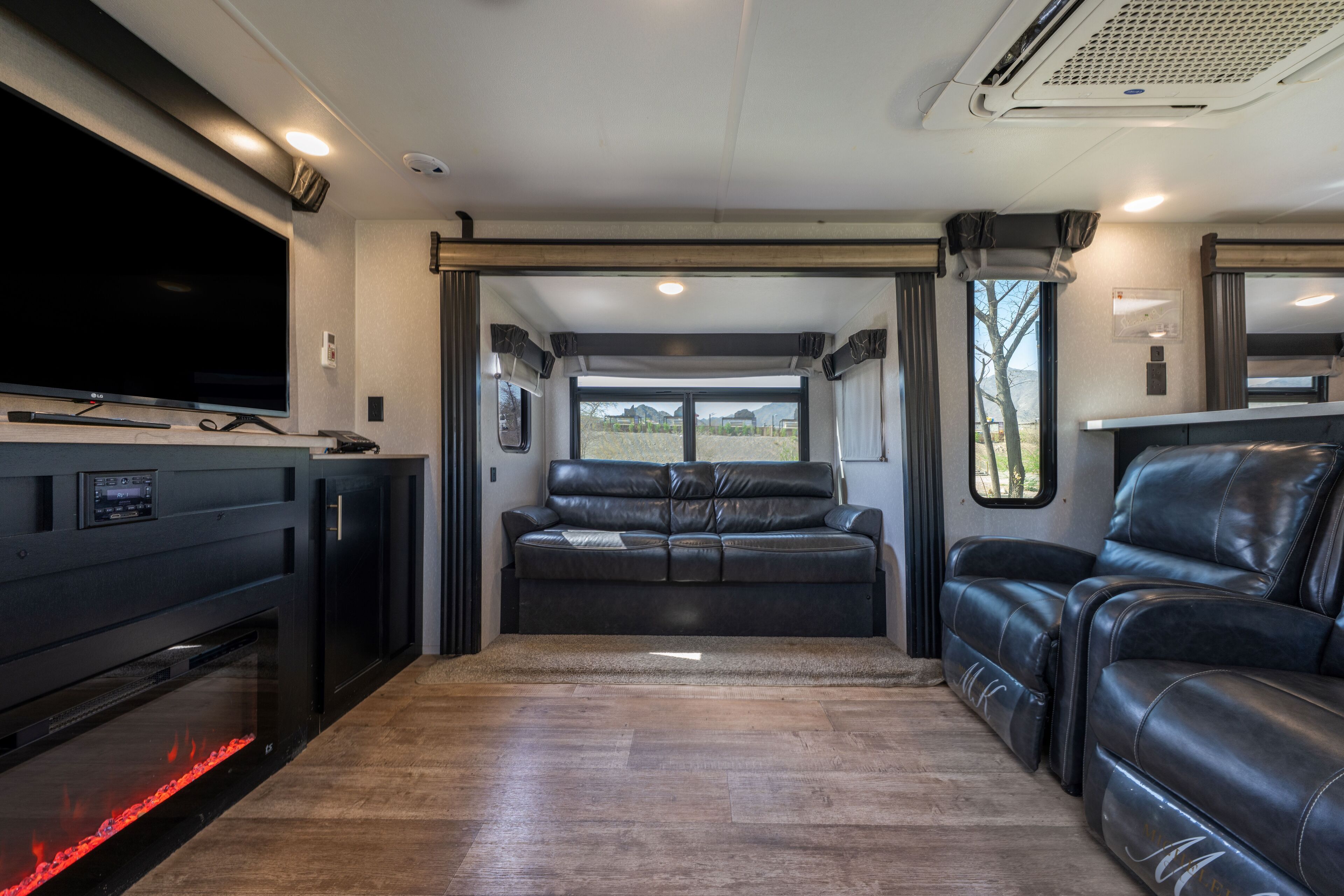 Un interior moderno de autocaravana con televisor de pantalla plana, asientos de cuero y chimenea.