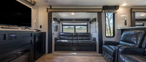 Un interior moderno de autocaravana con televisor de pantalla plana, asientos de cuero y chimenea.
