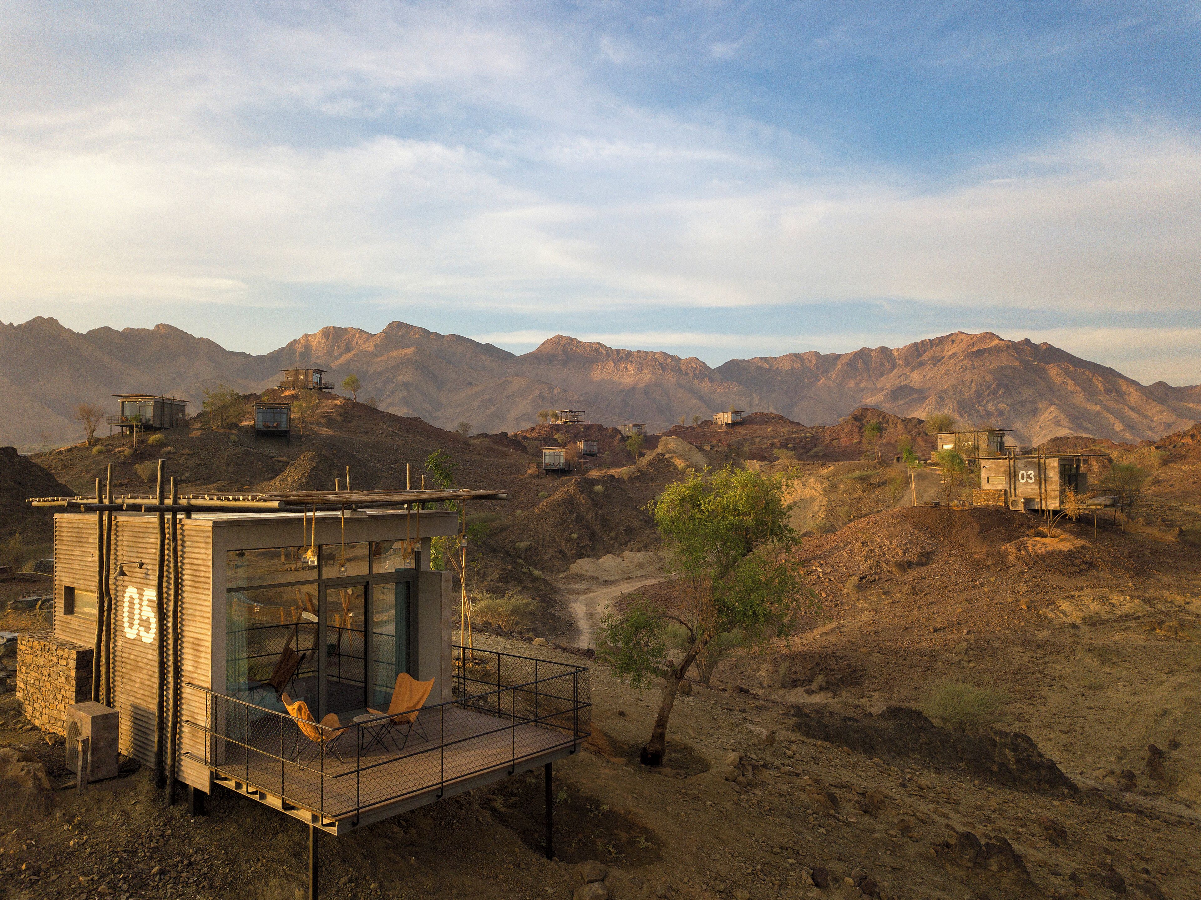 Un bâtiment moderne et minimaliste, doté d’une façade en verre, situé dans un paysage montagneux accidenté.