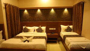 A hotel room with two beds, a nightstand, and a headboard with built-in lighting. - Horizon Inn (Chennai)