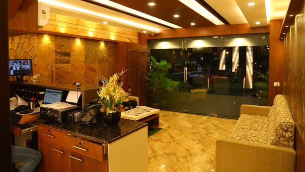 A modern hotel lobby with a reception desk, a sofa, and a large window overlooking the street. - Horizon Inn (Chennai)