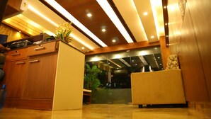 A modern kitchen with wooden cabinets, a countertop, and a vase with flowers. - Horizon Inn (Chennai)