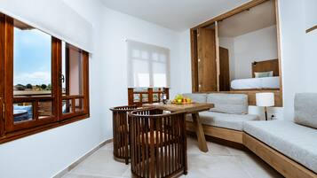 Een moderne woonkamer met een bank, een eettafel met stoelen en uitzicht door een raam.