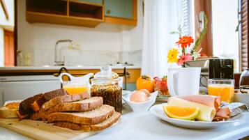 Una mesa de desayuno con tostadas, huevos, jamón, queso y jugo de naranja.