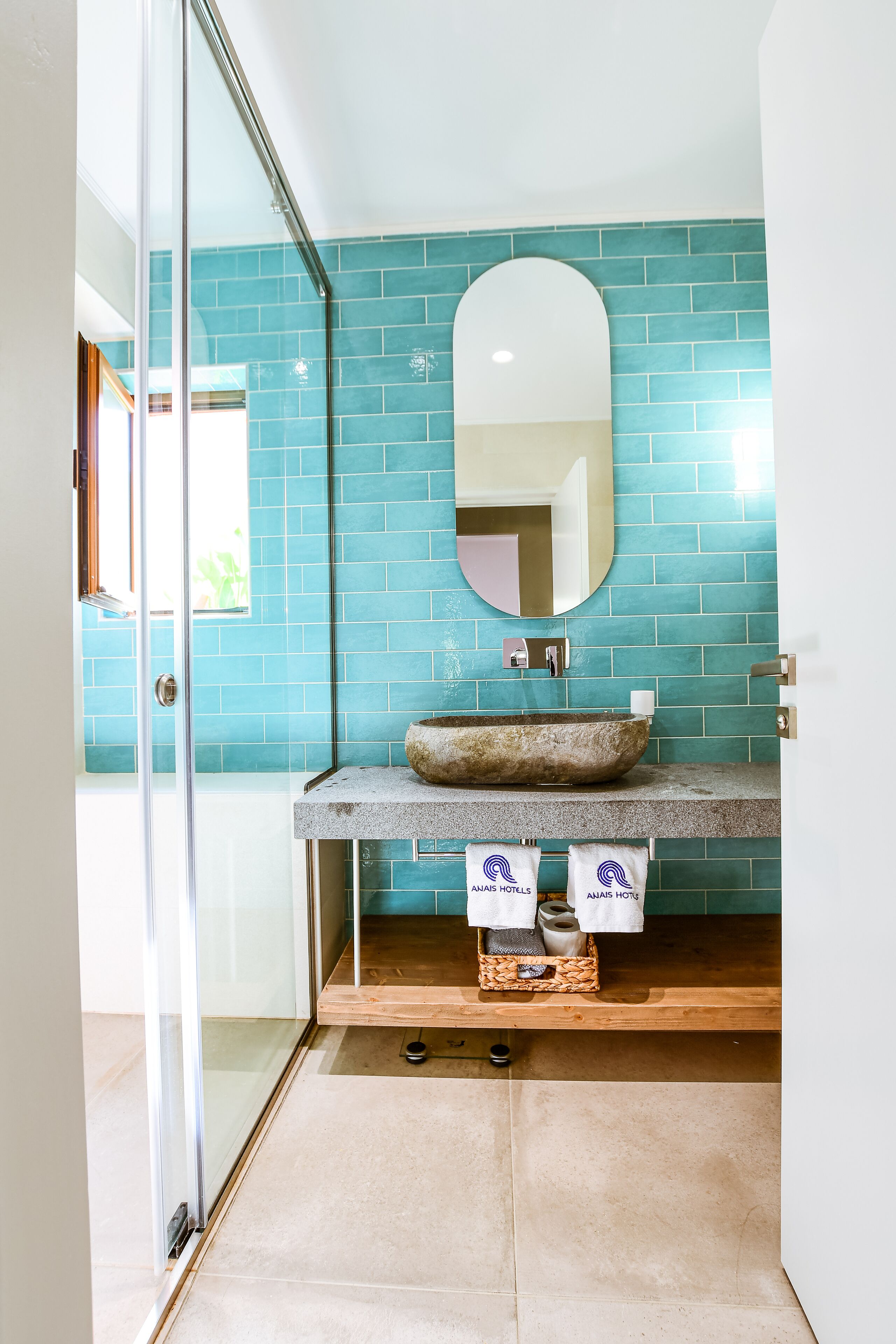 Une salle de bain avec une porte de douche en verre, un lavabo en pierre et un mur recouvert de carreaux bleus.