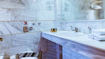 Un baño moderno con azulejos de mármol, un espejo grande, un lavabo y un inodoro.