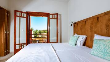 Un dormitorio con cama, cabecera de madera y vistas a un balcón con plantas y cielo despejado.