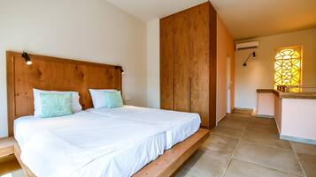 A bedroom with a wooden headboard, a bed with white bedding, and a small bench at the foot of the bed.