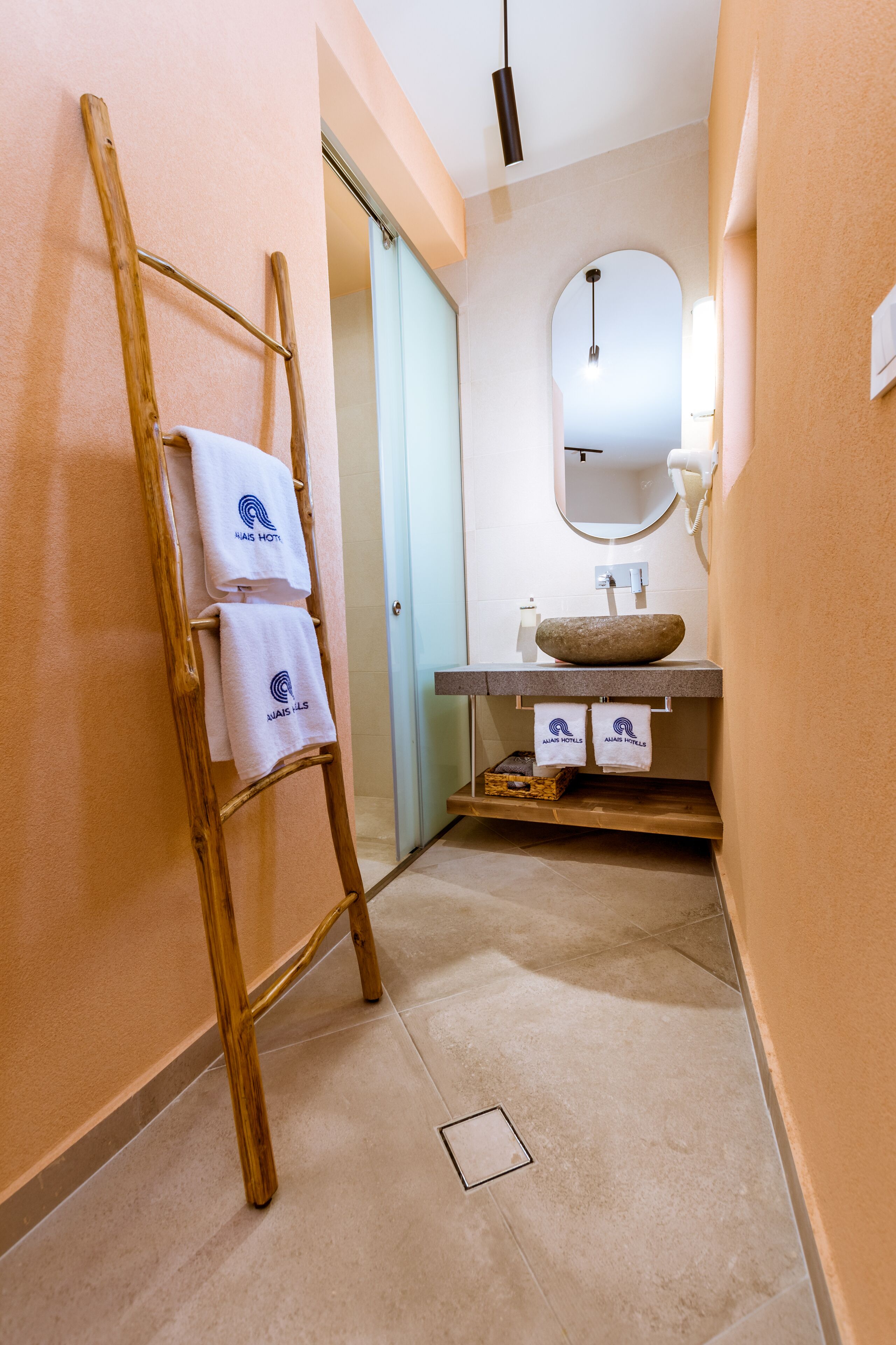 A bathroom with a wooden ladder, a sink with a stone basin, and towels hanging on the wall.