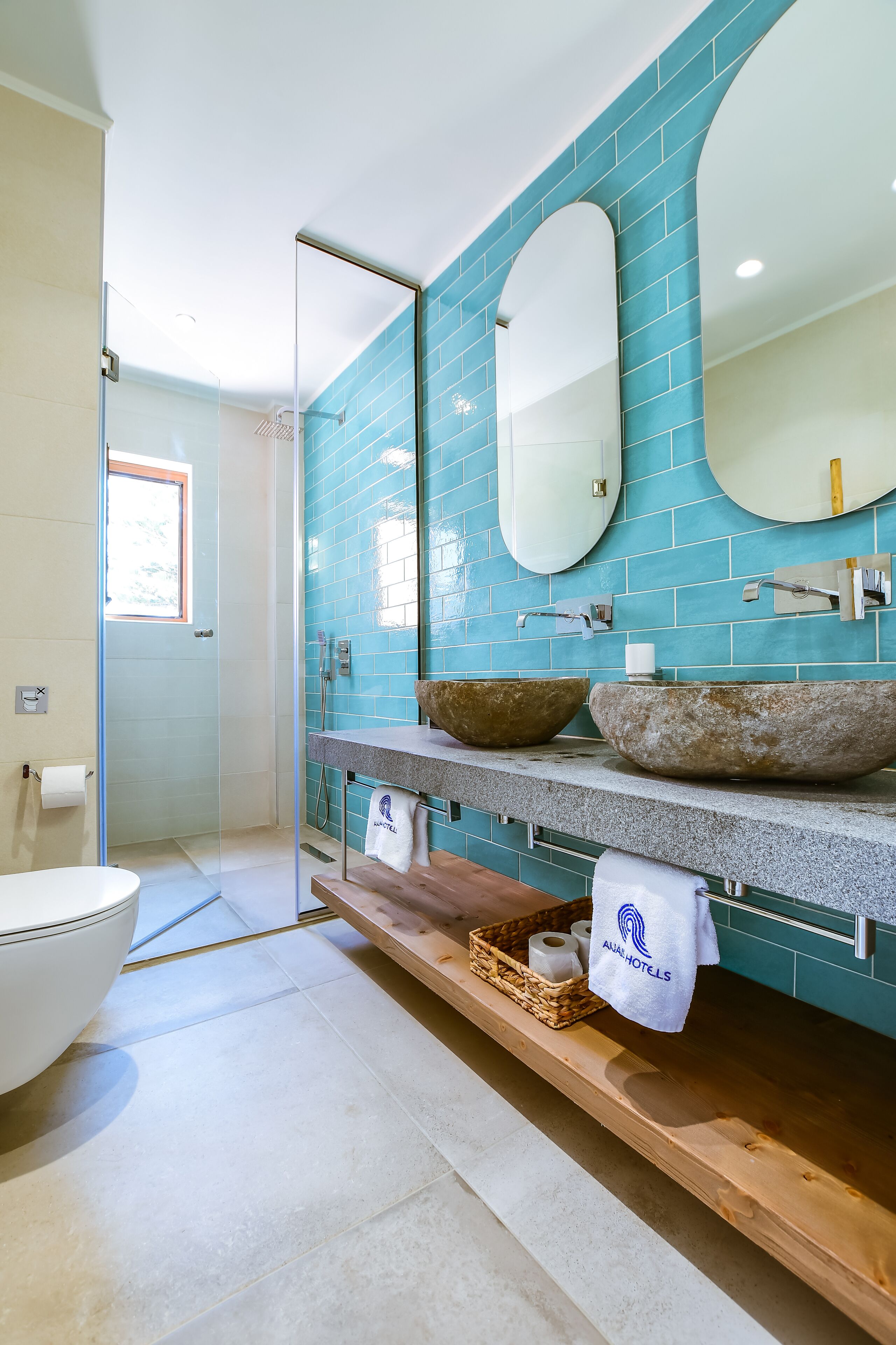 A bathroom with a glass shower enclosure, a white toilet, and a sink with a stone basin.