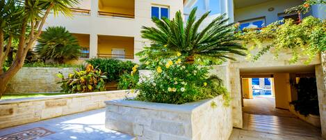 A modern building with a courtyard, stone steps, and lush greenery.