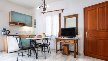 A compact kitchen with a dining area, a television, and a wooden door.