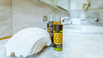 A bathroom with a marble sink, a white towel, and a bottle of olive oil conditioner.