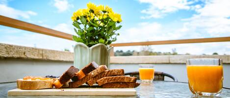 A table with toast, a glass of orange juice, and a vase of yellow flowers.