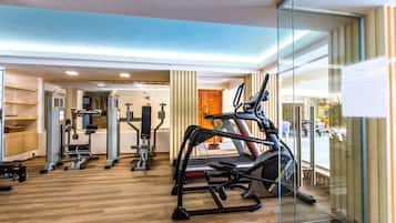 A modern gym with various exercise equipment, including treadmills and weight machines, and a wooden floor.