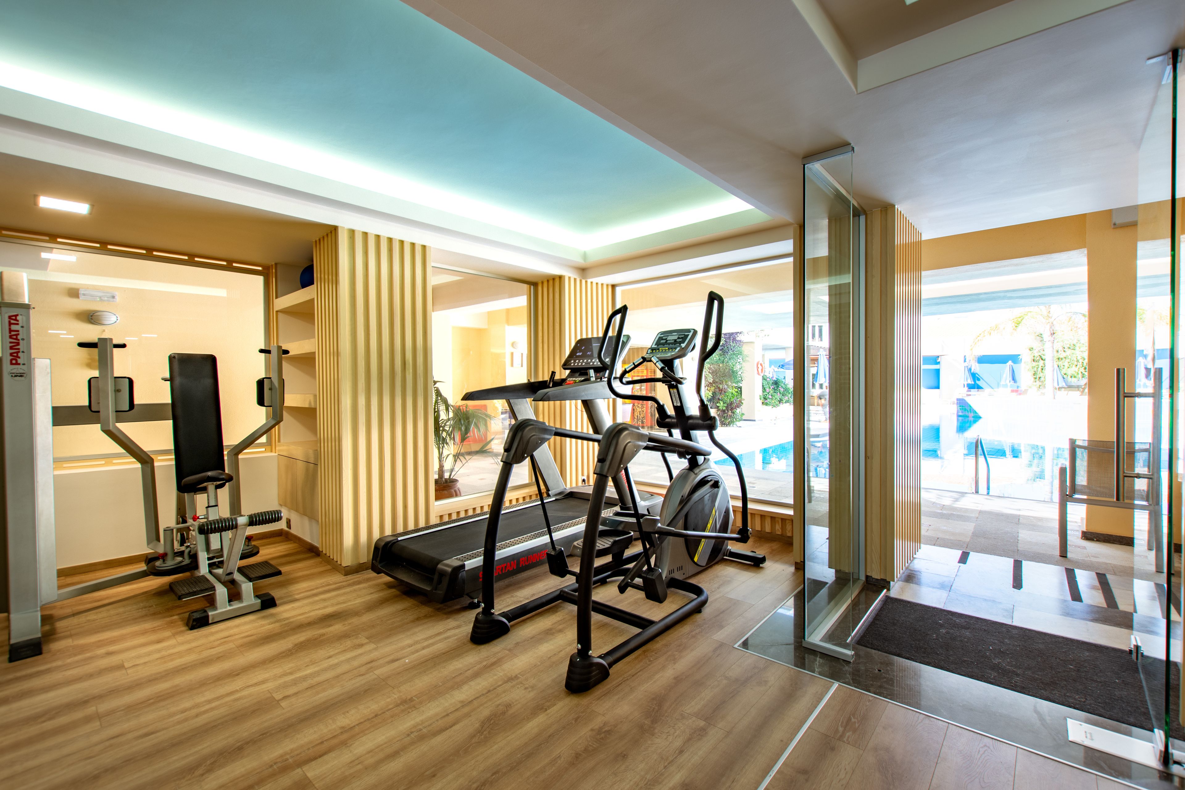 A gym with exercise equipment, a treadmill, and a mirrored wall.