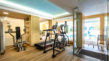 Ein Fitnessraum mit Trainingsgeräten, Laufband und einer Spiegelwand.