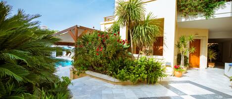 A courtyard with a pool, potted plants, and a tiled floor.