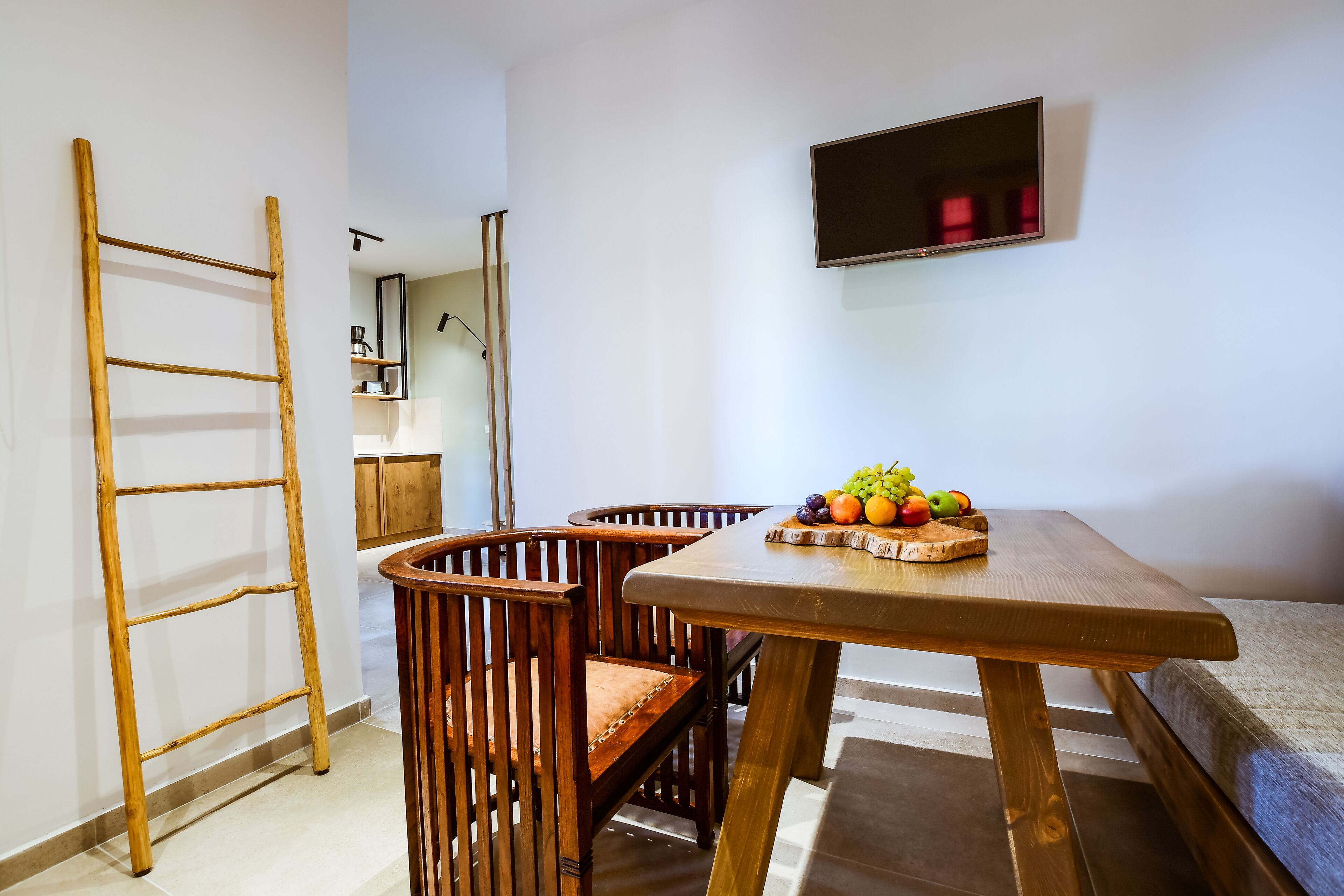 A dining area with a wooden table, chairs, and a fruit bowl.