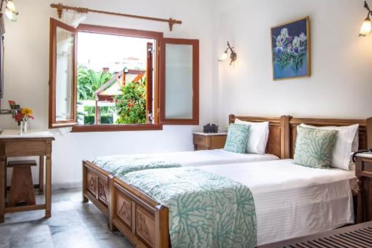 Une chambre avec un grand lit, un bureau et une fenêtre donnant sur un paysage verdoyant.