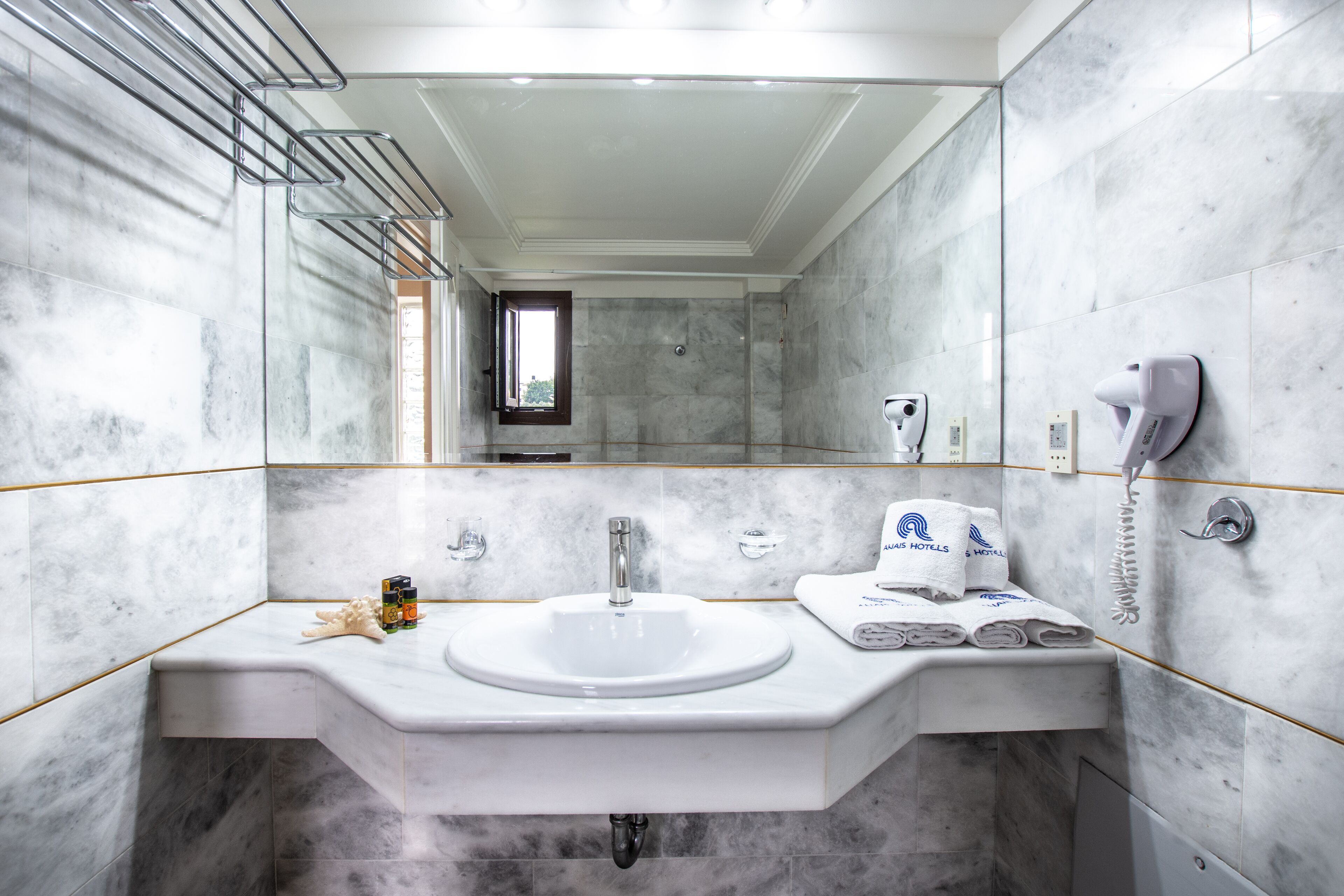 A modern bathroom with a marble sink, a mirror, and a towel rack.