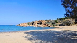 A beach with clear blue water, sandy shore, and rocky cliffs. - Anais Collection Hotels & Suites by GHH (Chania)